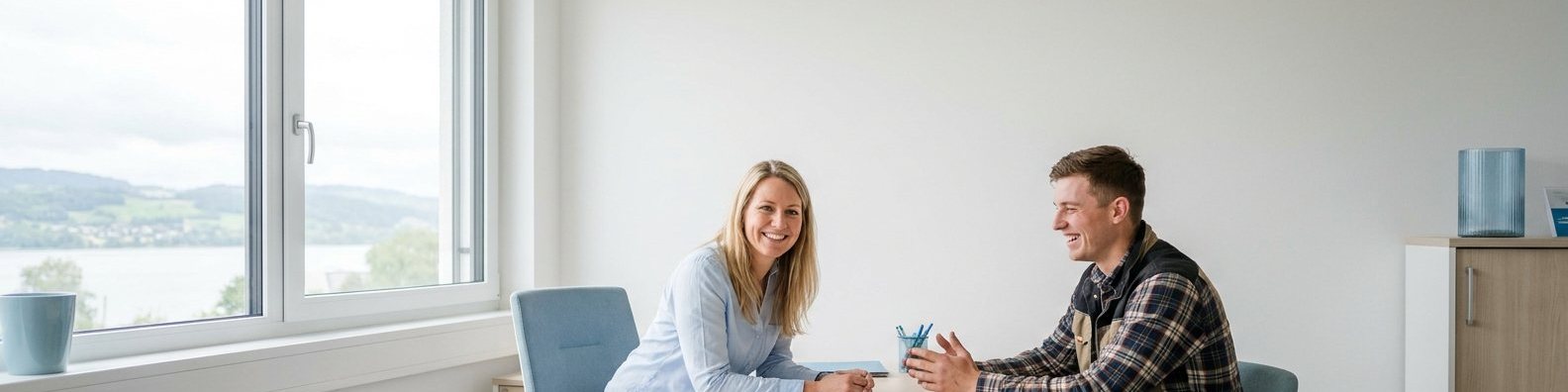 Beraterin und Bewerber im Gespräch am Tisch, im Fenster der Bodensee